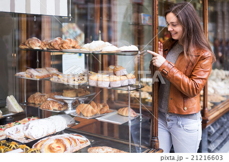 Brunette looking at fancy cakes 21216603