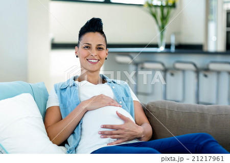Pregnant woman relaxing on sofa in living room Pregnant woman relaxing on sofa in living room 21217961