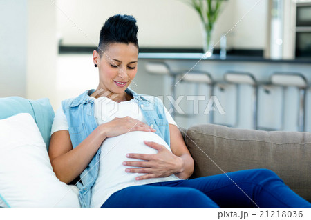 Pregnant woman relaxing on sofa in living room 21218036