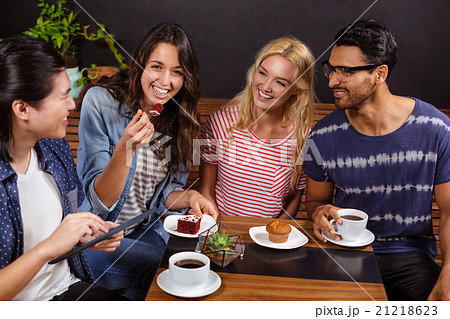 Smiling friends enjoying coffee together and using technologies 21218623