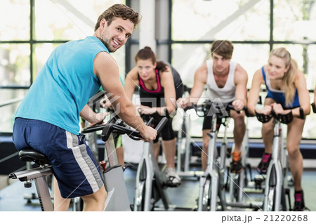 Fit group of people using exercise bike together 21220268