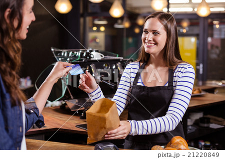Smiling woman giving credit card to barista Smiling woman giving credit card to barista 21220849