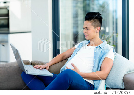 Pregnant woman relaxing on sofa with her laptop Pregnant woman relaxing on sofa with her laptop 21220858