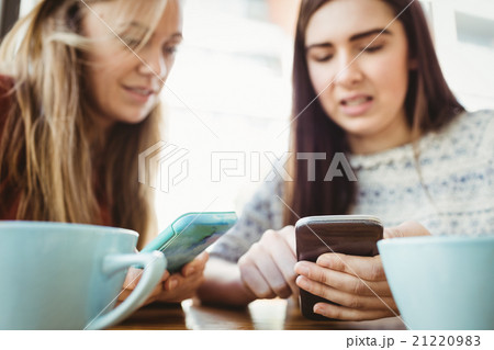 Friends using smartphone and having coffee Friends using smartphone and having coffee 21220983