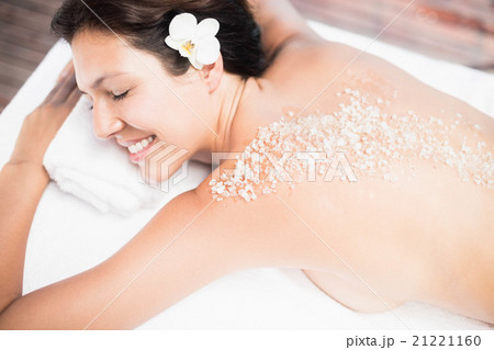 Woman lying on massage table with salt scrub on back Woman lying on massage table with salt scrub on back 21221160