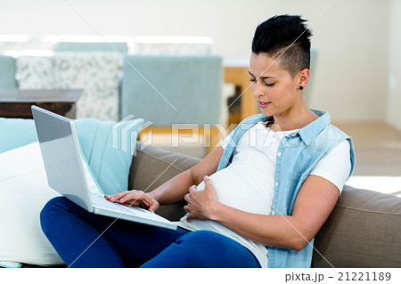 Pregnant woman relaxing on sofa with her laptop 21221189