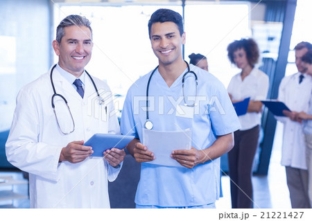 Doctors with digital tablet and medical report looking at camera Doctors with digital tablet and medical report looking at camera 21221427