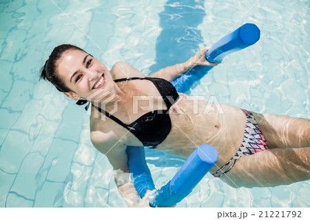 Pretty brunette in swimsuit swimming with a foam roller Pretty brunette in swimsuit swimming with a foam roller 21221792