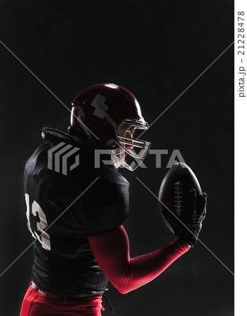 American football player posing with ball on black 21228478