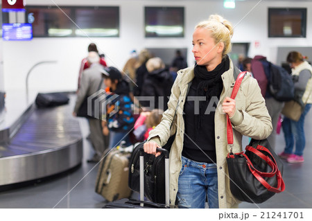 Female traveler transporting luggage in airport. 21241701