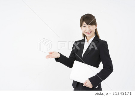ノートパソコンを片手に提案しながら優しく微笑む若く美人で可愛いスーツ姿の女性モバイルキャリアウーマンの写真素材