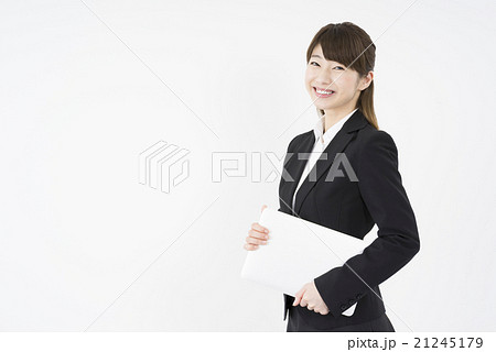 ノートパソコンを片手に持ち優しく微笑む若く美人で可愛いスーツ姿の女性モバイルキャリアウーマンノマドの写真素材