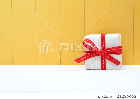 Cute white and red gift box on yellow background Cute white and red gift box on yellow background 21250402