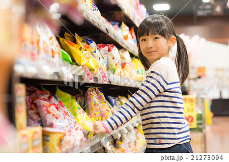 スーパーのお菓子売り場でお菓子を選ぶ女の子の写真素材