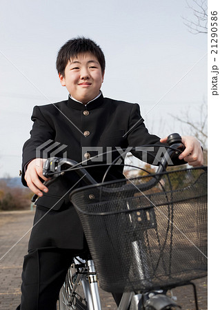 学生服を着て自転車通学をする男子中学生の写真素材