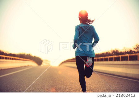 young woman runner running at sunrise city road 21302412