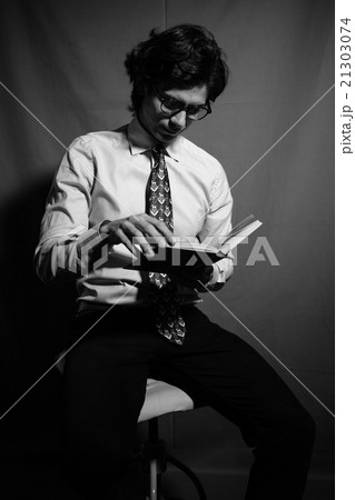Young man reading a book with glasses. Young man reading a book with glasses. 21303074