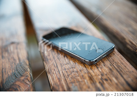 phone in the rain on a wooden bench 21307018