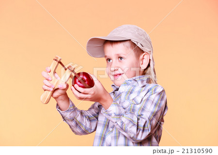 Young boy use sling shot shoot apple. 21310590