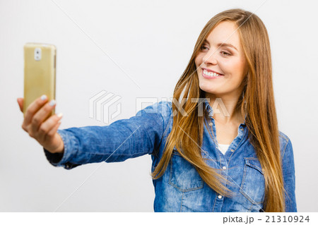 Woman in denim shirt taking self picture with phone 21310924