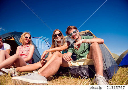 Teenagers sitting on the ground in front of tents Teenagers sitting on the ground in front of tents 21315767