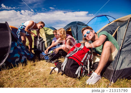 Teenagers sitting on the ground in front of tents Teenagers sitting on the ground in front of tents 21315790