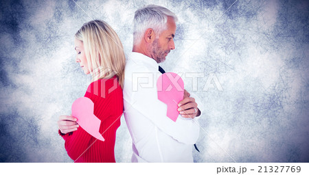 Composite image of couple holding two halves of broken heart Composite image of couple holding two halves of broken heart 21327769