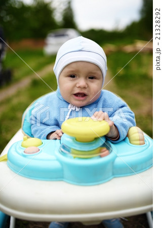 Crying cute baby in baby walker walks outdoors Crying cute baby in baby walker walks outdoors 21328292
