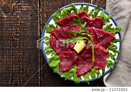 Carpaccio on the white plate on the wooden table 21372802