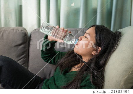 Pretty young girl drinking water on couch 21382494