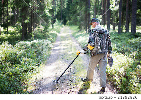 Treasure hunter with metal detector 21392826