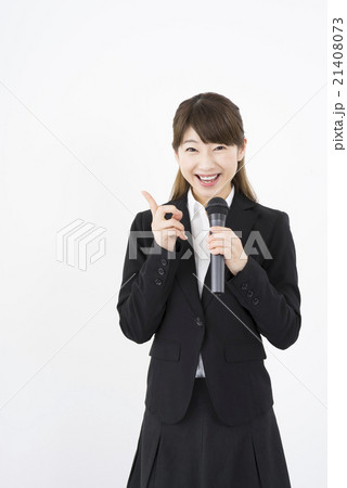 プレゼンテーター マイクを持ち優しく微笑むスーツを着た若く美人で可愛い女性イベントコンパニオン縦画面の写真素材