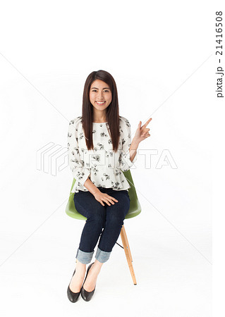 椅子に座って指さしポーズ 女性の写真素材