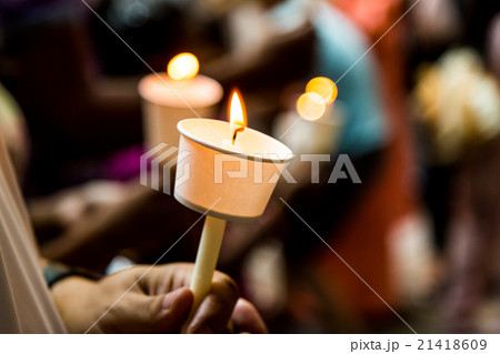 Closeup of people holding candle vigil in darkness 21418609