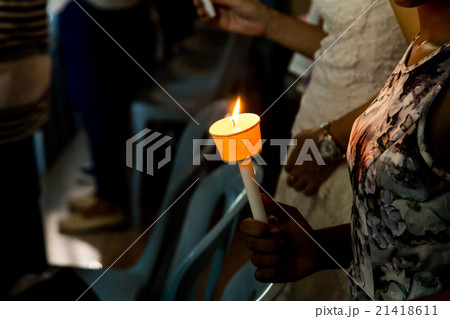 Closeup of people holding candle vigil in darkness 21418611