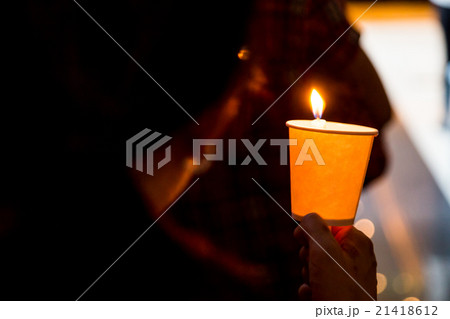 Closeup of people holding candle vigil in darkness 21418612