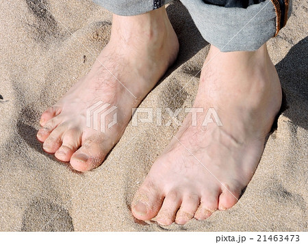 砂浜に立つ男性のはだしの足の写真素材
