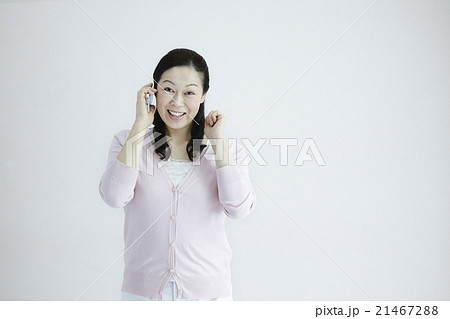 自然光白バック40代女性ミドルエイジ　スマホ／携帯電話喜びのチュエーションの対応とジェスチャー 21467288