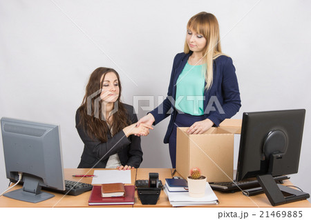 Girl in office standing with a smile in front of the box and shakes hands with a colleague 21469885