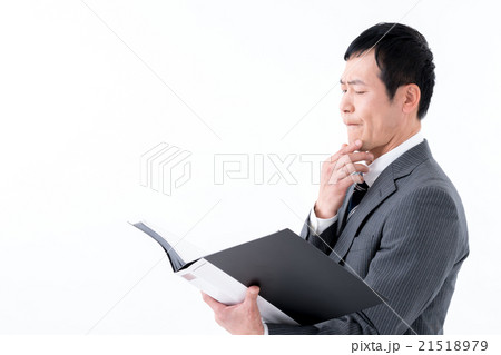 資料を見て厳しい表情の男性 21518979