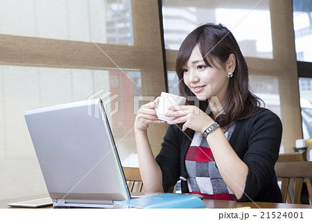 コーヒーを飲みながらパソコンを見る若い女性 カフェの写真素材