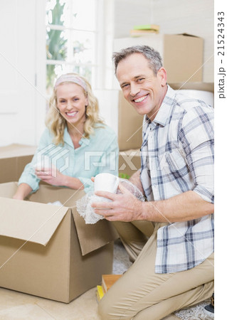Smiling couple packing mug in a box Smiling couple packing mug in a box 21524343