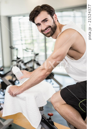 Smiling man on exercise bike looking at the camera Smiling man on exercise bike looking at the camera 21524377