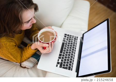 Smiling pretty woman using laptop while drinking coffee Smiling pretty woman using laptop while drinking coffee 21524658