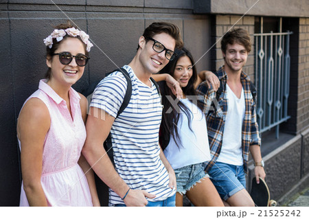 Hip friends smiling at the camera and leaning against wall 21525242