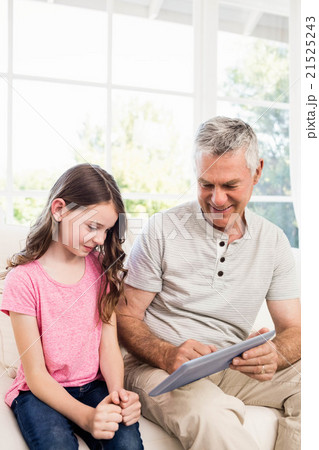 Smiling grandfather and granddaughter using tablet 21525243