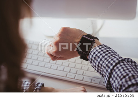 Over the shoulder view of businesswoman watching her smart watch 21525559