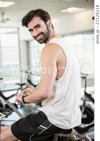 Smiling man on exercise bike using smartwatch Smiling man on exercise bike using smartwatch 21526218