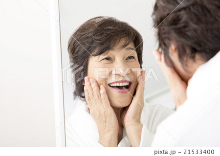 バスロープでお肌の手入れをするシニア女性 21533400