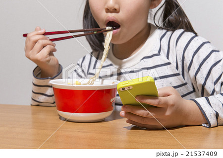 カップラーメンを寂しく食べる女の子の写真素材